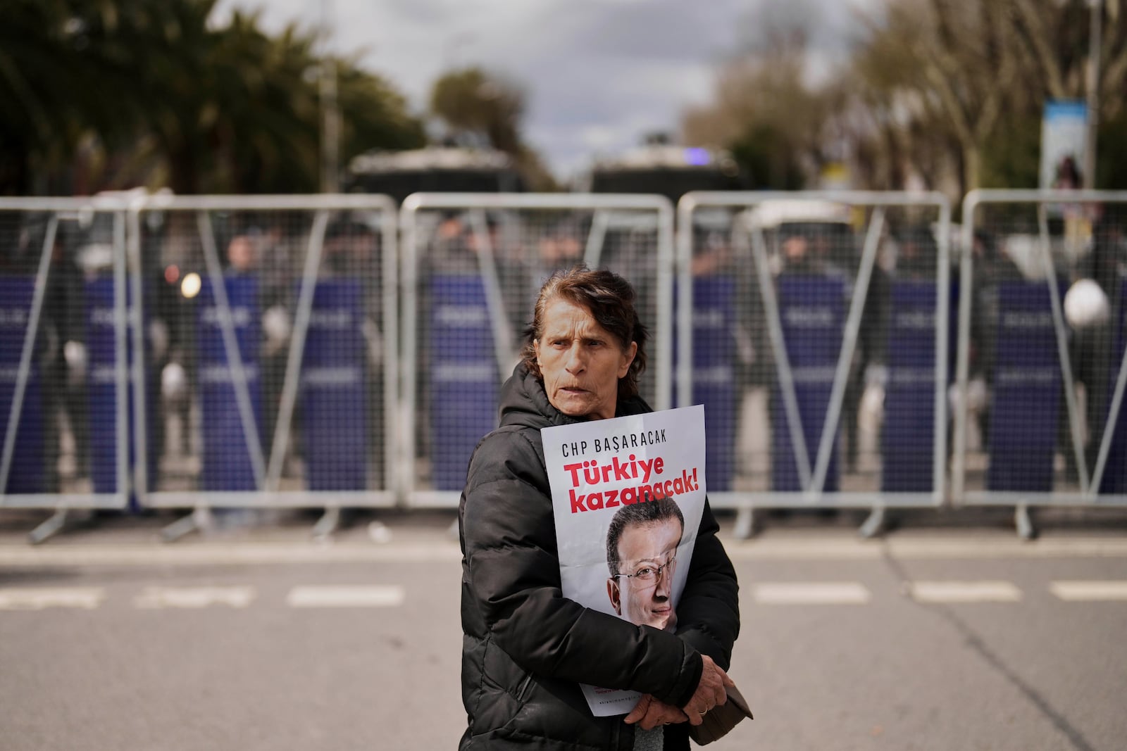 A woman protests, holding a poster of Istanbul Mayor Ekrem Imamoglu, in front of a police cordon blocking the roads leading to the Vatan Security Department, where Imamoglu is expected to be taken following his arrest in Istanbul, Turkey, Wednesday, March 19, 2025. (AP Photo/Francisco Seco)