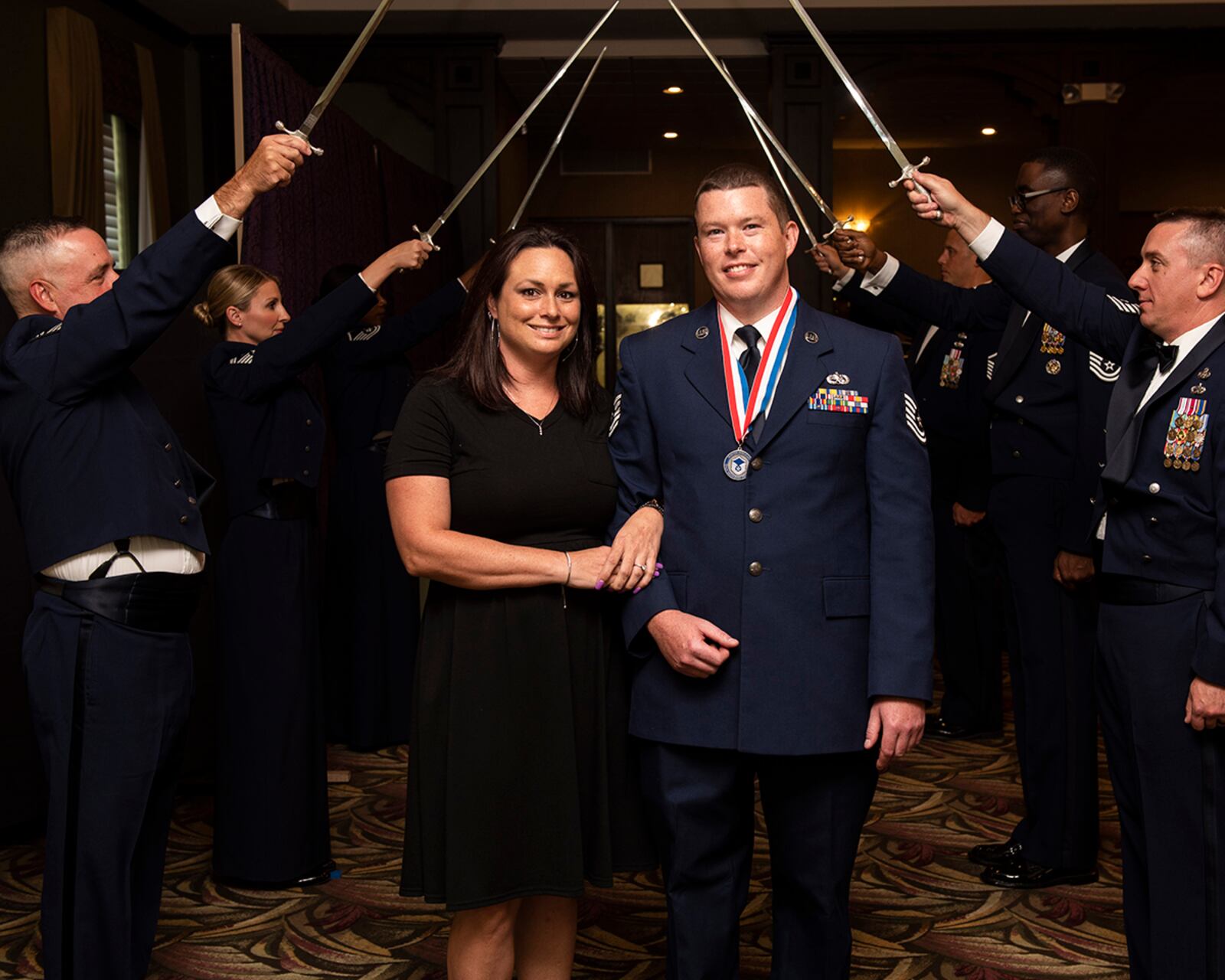 A promotee and his wife pose for a photo after walking through a saber cordon July 23 during the Senior Noncommissioned Officer Induction Ceremony. U.S. AIR FORCE PHOTO/WESLEY FARNSWORTH