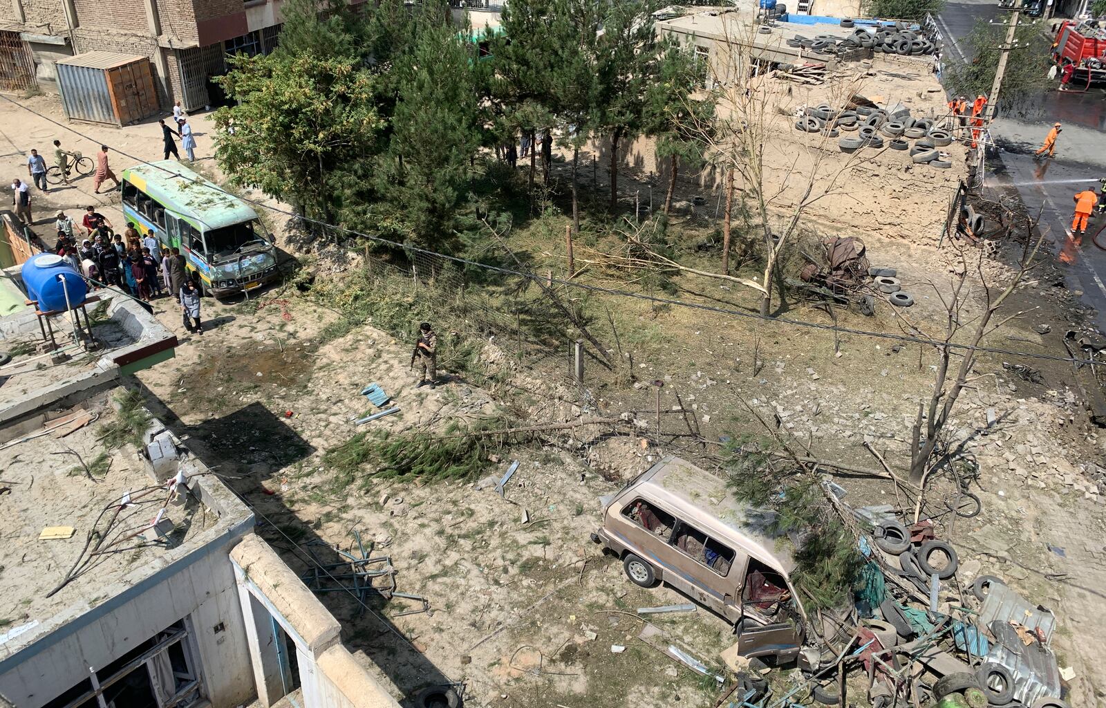 Bystanders, left, look at the scene of an explosion as Afghan municipality workers, right, work at the site of an explosion in Kabul, Afghanistan, Wednesday, Sept. 9, 2020. Spokesman for Afghanistan's Interior Ministry said the bombing that targeted the convoy of the country's first vice president on Wednesday morning killed several people and wounded more than a dozen others, including several of the vice president's bodyguards.(AP Photo/Rahmat Gul)