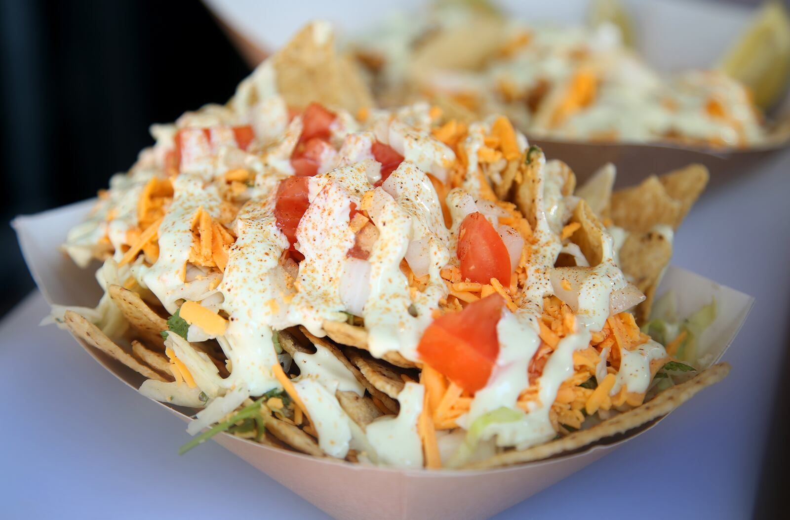 The Nacho Salad from Mamma'z Boyz food trailer is made with tortilla chips topped with slaw mix, shredded cheddar cheese, onions, tomatoes and the the Mamma's Boyz trailer made avacado cream sausce. LISA POWELL / STAFF