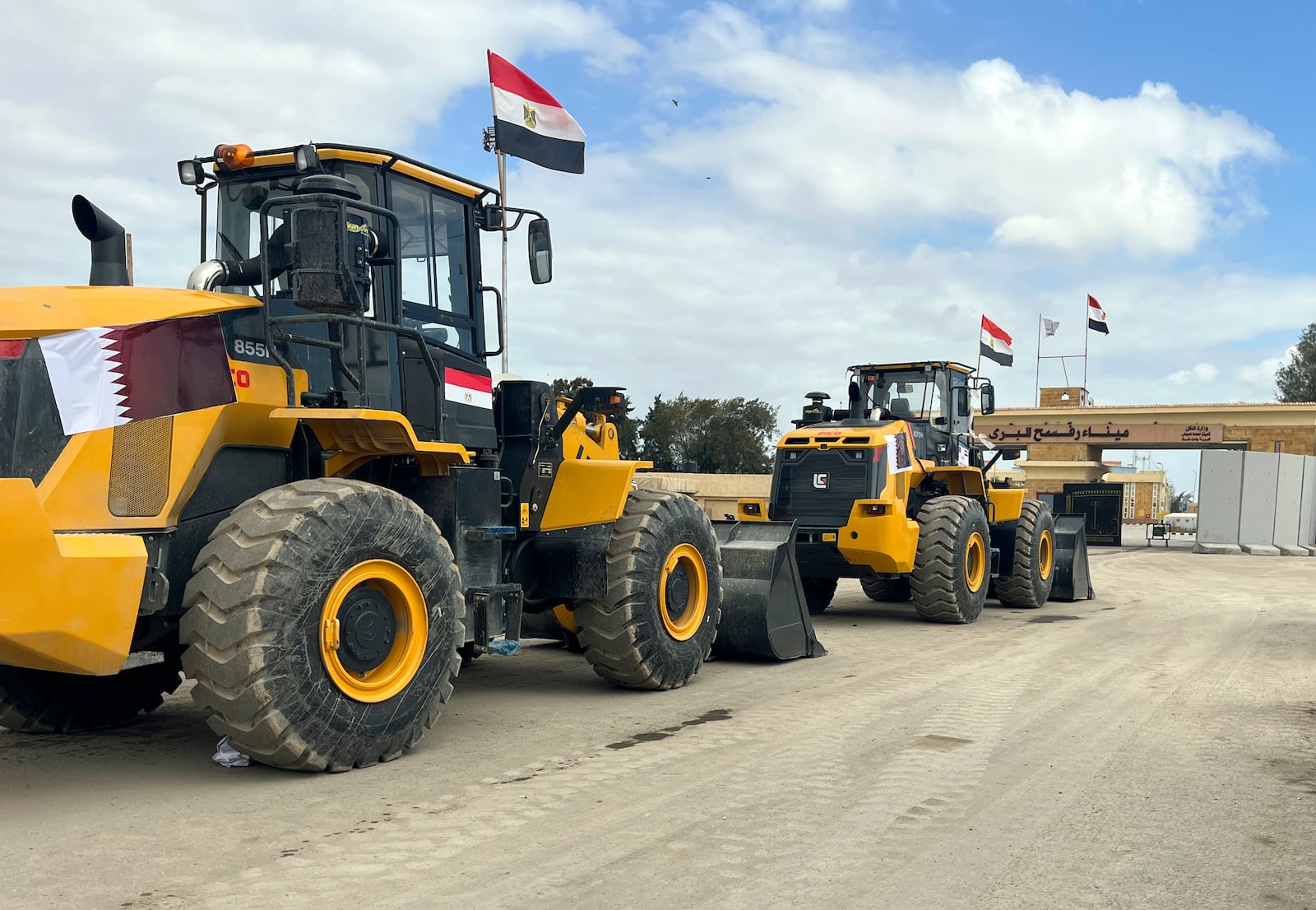 Bulldozers with Egyptian and Qatar flags wait to enter Gaza at the Rafah border crossing between Egypt and the Gaza Strip, Thursday, Feb. 13, 2025. (AP Photo/Mohamed Arafat)