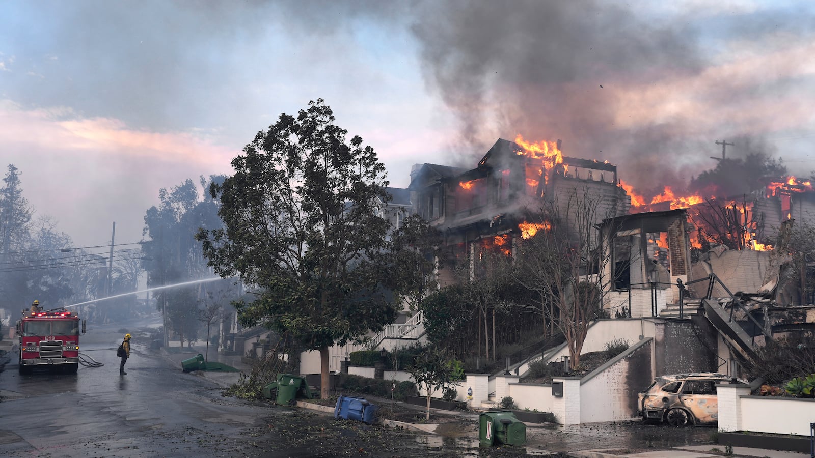 Los Angeles Fire Department firefighters work to extinguish a house fire as the Palisades Fire ravages a neighborhood amid high winds in the Pacific Palisades neighborhood of Los Angeles, Wednesday, Jan. 8, 2025. (AP Photo/Damian Dovarganes)