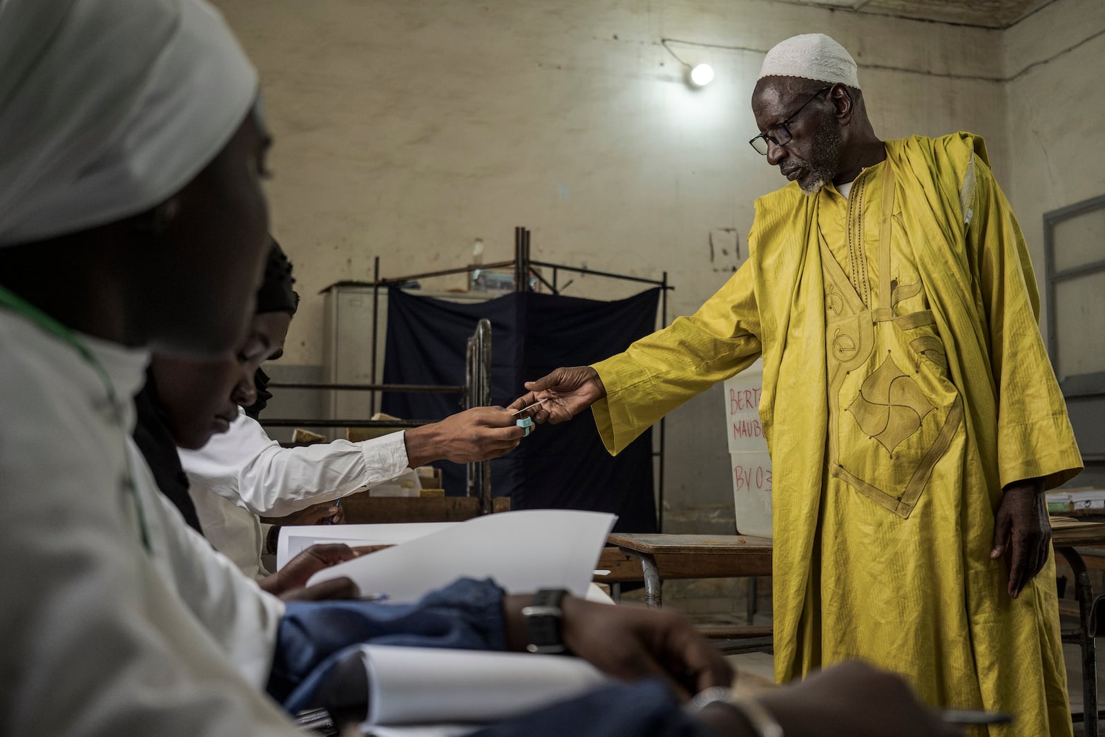 A man has his identity verified before casting his vote during legislative elections in Dakar, Senegal Sunday, Nov. 17, 2024. (AP Photo/Annika Hammerschlag)