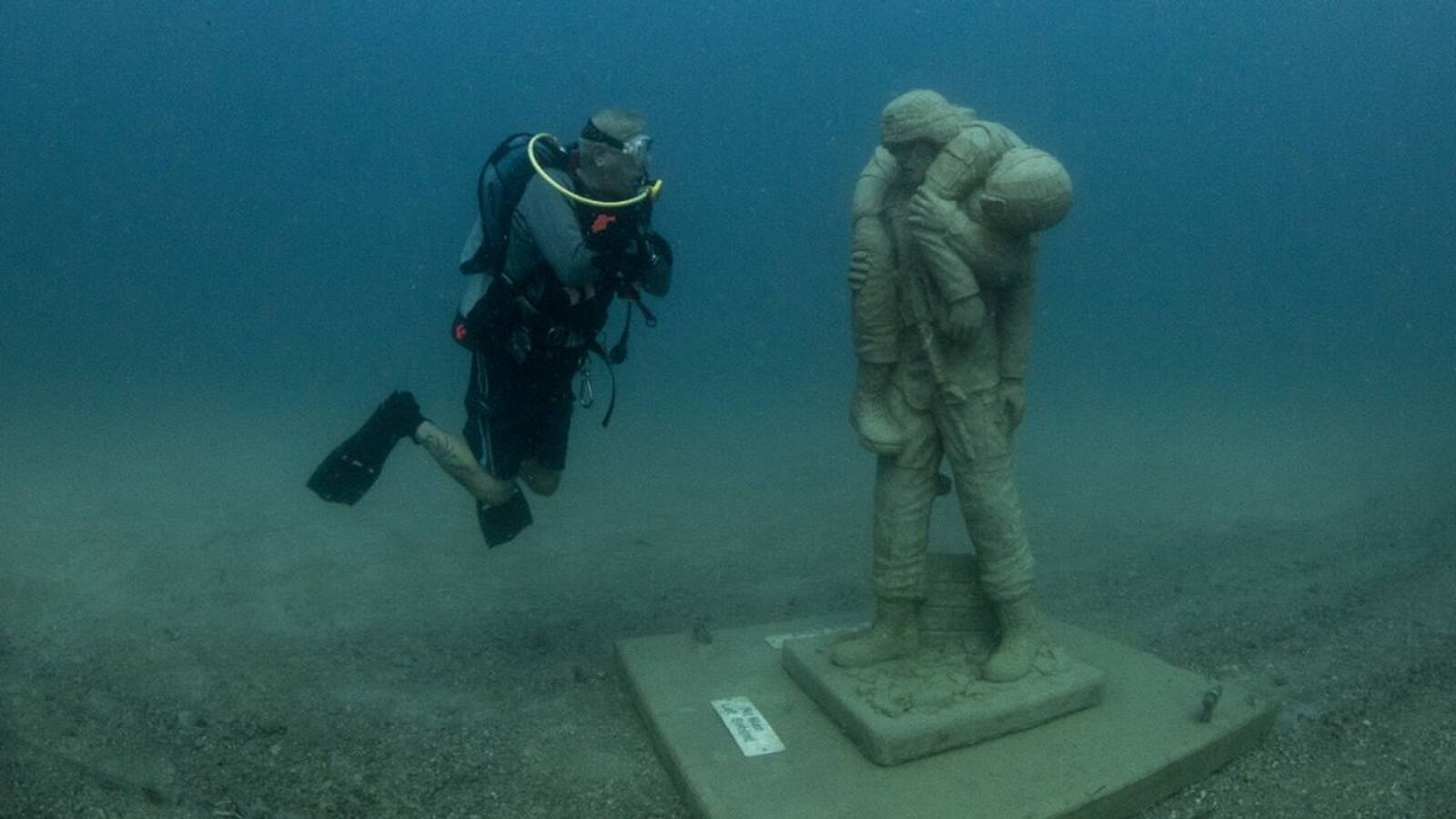 A diver checks out a memorial to a veteran carrying a fellow soldier at the Circle of Heroes memorial in the Gulf of Mexico off the Florida coast.