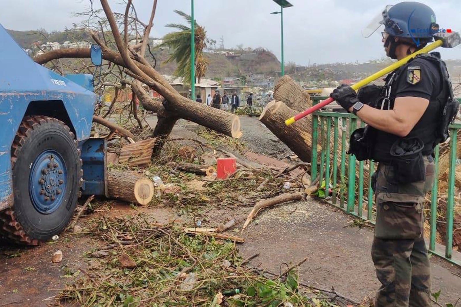 This photo provided on Monday Dec.16, 2024 by the Gendarmerie Nationale, shows a member of the Gendarmerie Nationale watching an armored vehicle clearing a road Sunday, Dec. 15, 2024 in Mayotte as France rushed rescue teams and supplies to its largely poor overseas department in the Indian Ocean that has suffered widespread destruction. (Gendarmerie Nationale via AP)