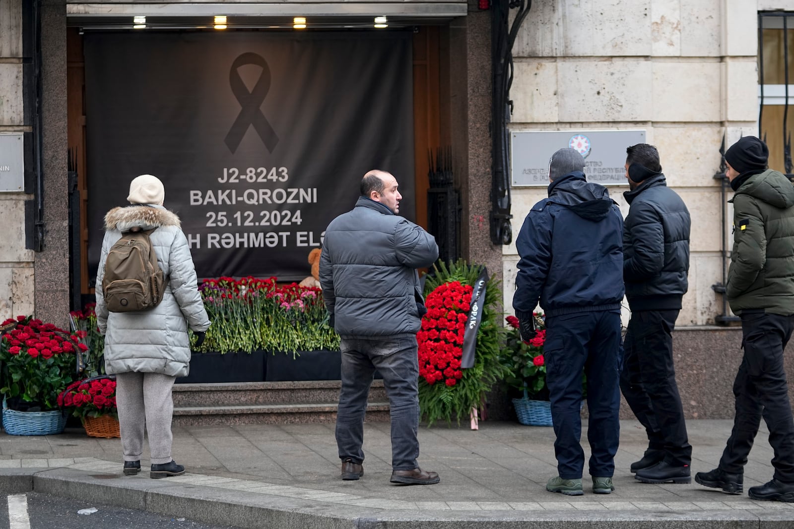 People stand at a street memorial outside the Azerbaijani embassy in Moscow, Russia, on Saturday, Dec. 28, 2024, in the memory of victims of the Azerbaijan Airlines Embraer 190 that crashed near the Kazakhstan's airport of Aktau. (AP Photo/Pavel Bednyakov)