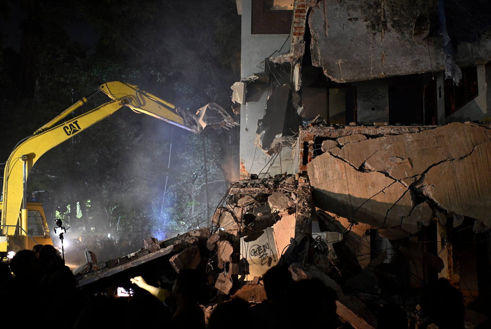 People watch as protesters use heavy machinery to demolish the residence of Sheikh Mujibur Rahman, Bangladesh's former leader and the father of the country's ousted Prime Minister Sheikh Hasina, at Dhanmondi, in Dhaka, Bangladesh, early Thursday, Feb. 6, 2025. (AP Photo/Mahmud Hossain Opu)