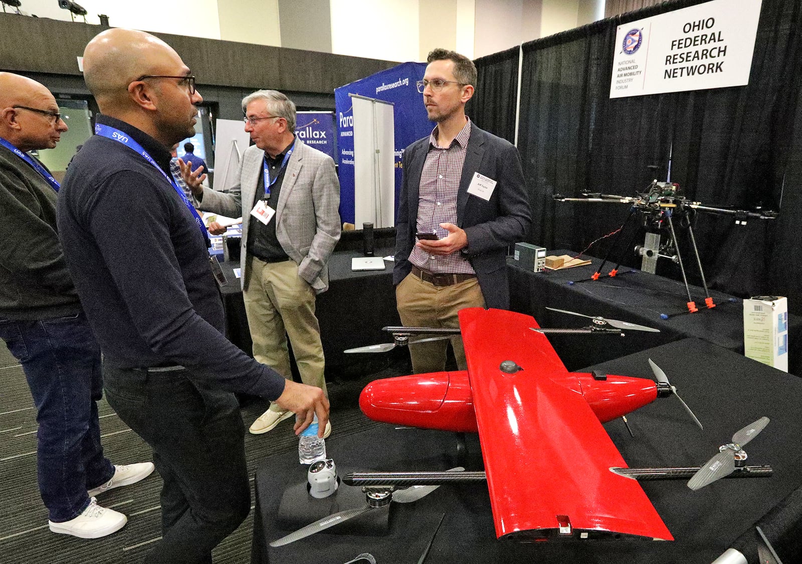 Pramod Abichandani, left, talks with Jeff Taylor at the Ohio Federal Research Network exhibit booth during the National Advanced Air Mobility Industry Forum Monday, August 22, 2022 at Clark State's Hollenbeck-Bailey Conference Center in Springfield. BILL LACKEY/STAFF