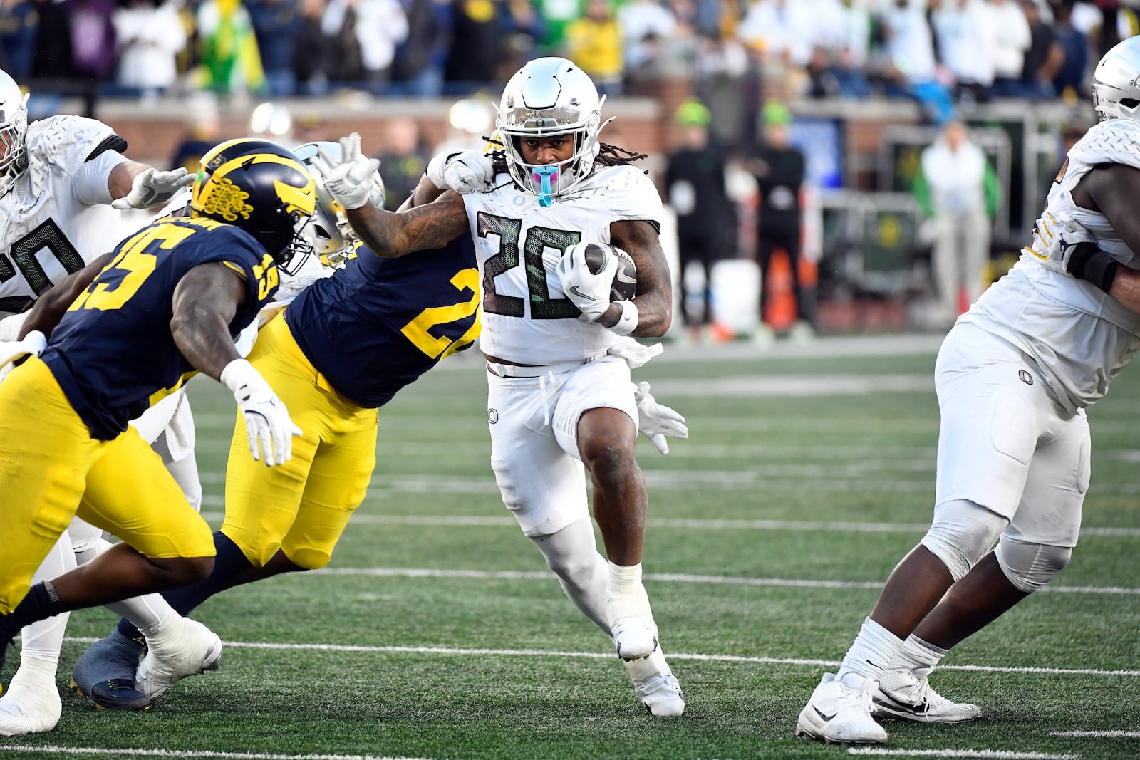 Oregon running back Jordan James (20) runs with the ball and is chased by Michigan linebacker Ernest Hausmann (15) and defensive lineman Rayshaun Benny (26) during the second half of an NCAA college football game, Saturday, Nov. 2, 2024, in Ann Arbor, Mich. Oregon defeated Michigan 38-17. (AP Photo/Jose Juarez)