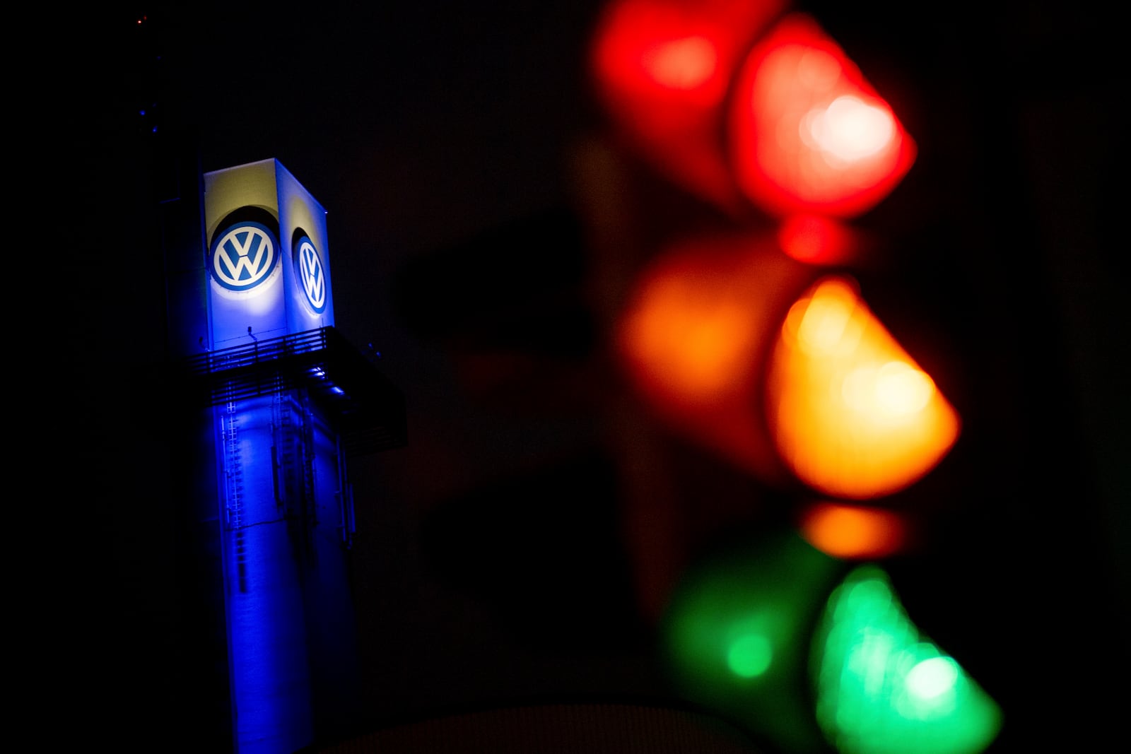 A traffic light shines in front of a Volkswagen logo at the Volkswagen plant in Osnabruck, Germany, Tuesday, Oct. 29, 2024. (Hauke-Christian Dittrich/dpa via AP)