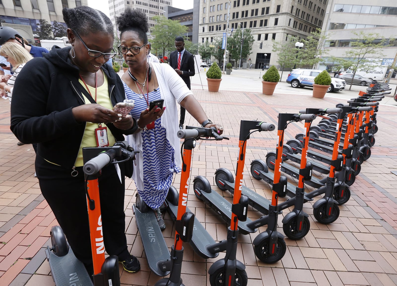 Lettia Younger, left, and Sheila Back log into the Spin Electric Scooters app at Courthouse Square before taking a test ride on the electric scooters. TY GREENLEES / STAFF