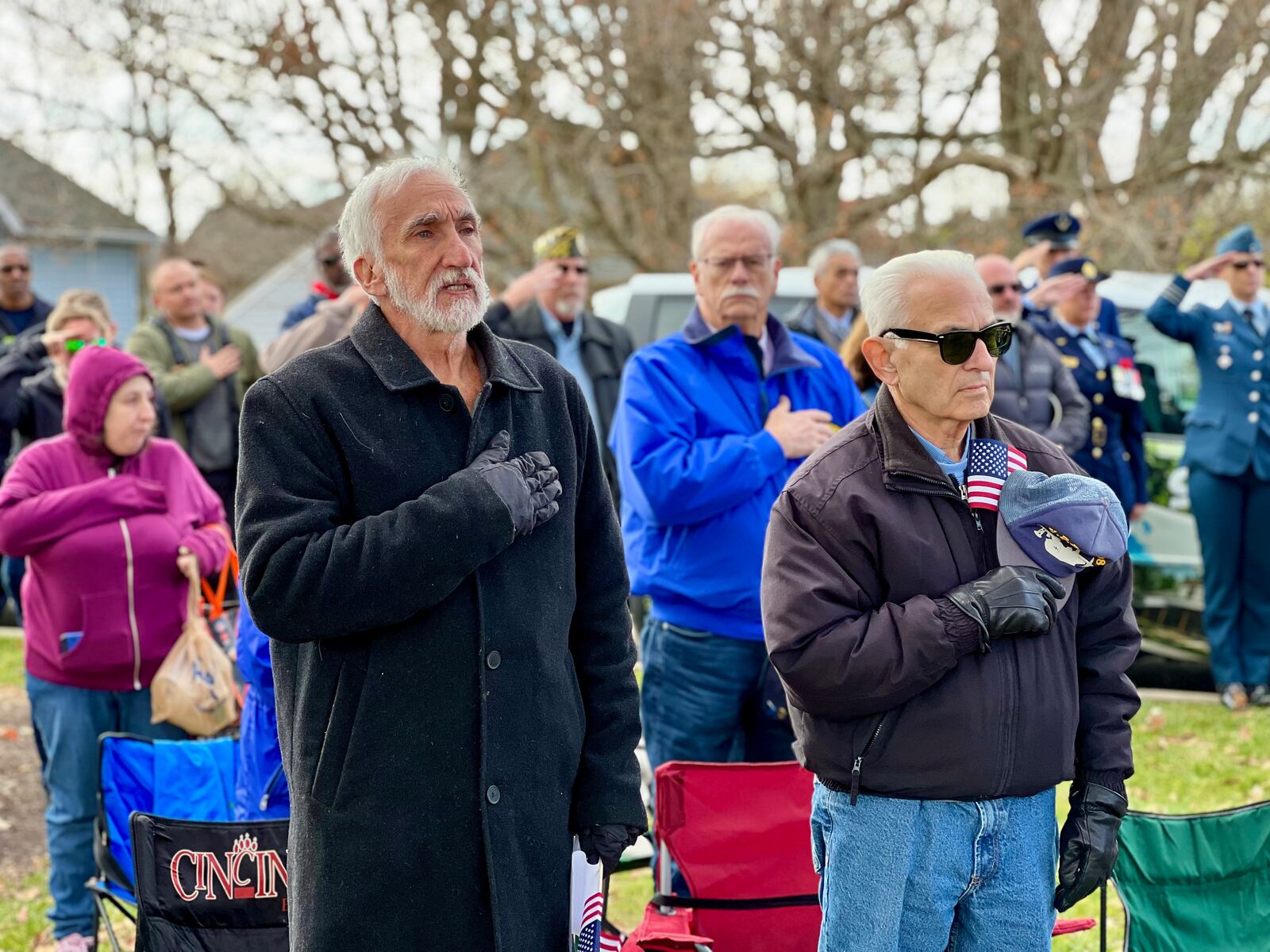 Attendees to Saturday's Veterans Day even in Beavercreek's Veterans Memorial Park stand for the national anthem. AIMEE HANCOCK/STAFF