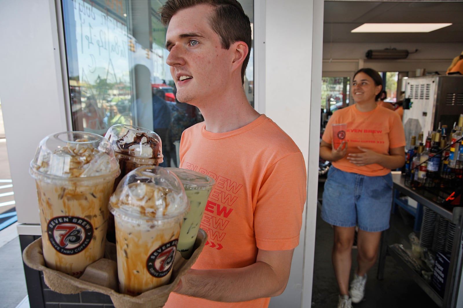 Seven Brew employee Austin Allen carries out a drink order to a customer before the ribbon cutting ceremony for Seven Brew's new Springfield location Tuesday, July 16, 2024. BILL LACKEY/STAFF