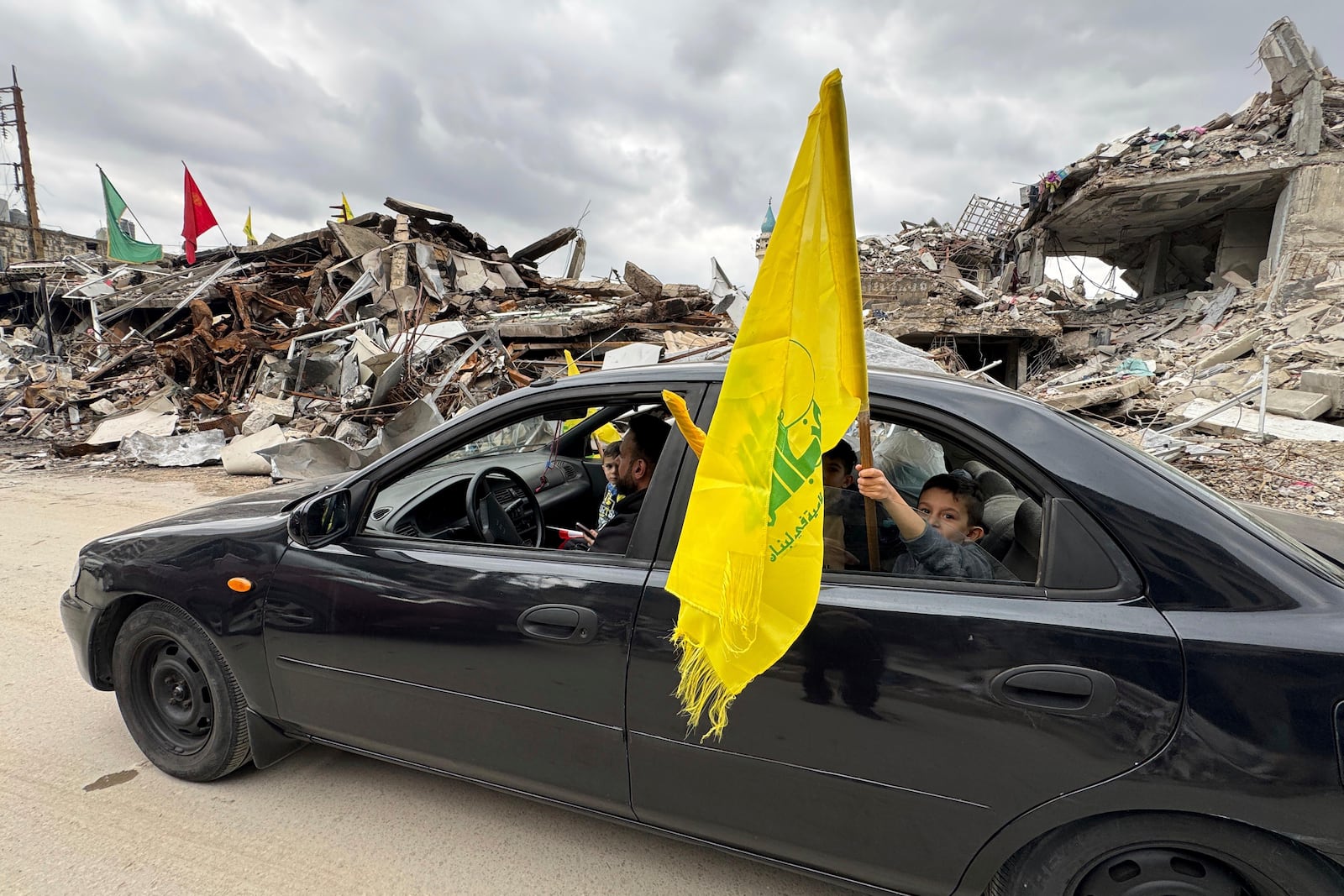 A boy holds a Hezbollah's flag, as displaced residents return to Nabatiyeh, southern Lebanon, Thursday, Nov. 28, 2024 following a ceasefire between Israel and Hezbollah that went into effect on Wednesday. (AP Photo/Bassam Hatoum)