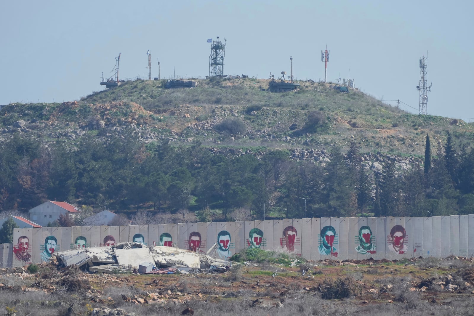 Posters of Hezbollah members on a border wall with Israel after they were defaced by Israeli troops during the Israel Hezbollah war in the town of Kfar Kila, southern Lebanon, Tuesday, Feb. 18, 2025. (AP Photo/Hassan Ammar)