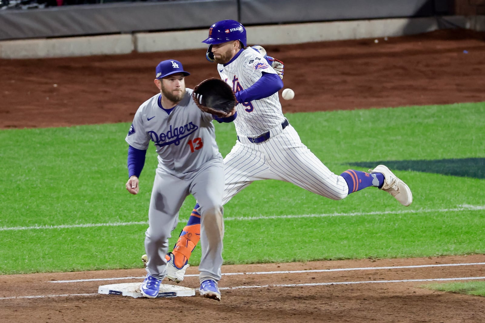 New York Mets' Brandon Nimmo is safe at first past Los Angeles Dodgers first baseman Max Muncy during the third inning in Game 4 of a baseball NL Championship Series, Thursday, Oct. 17, 2024, in New York. (AP Photo/Adam Hunger)