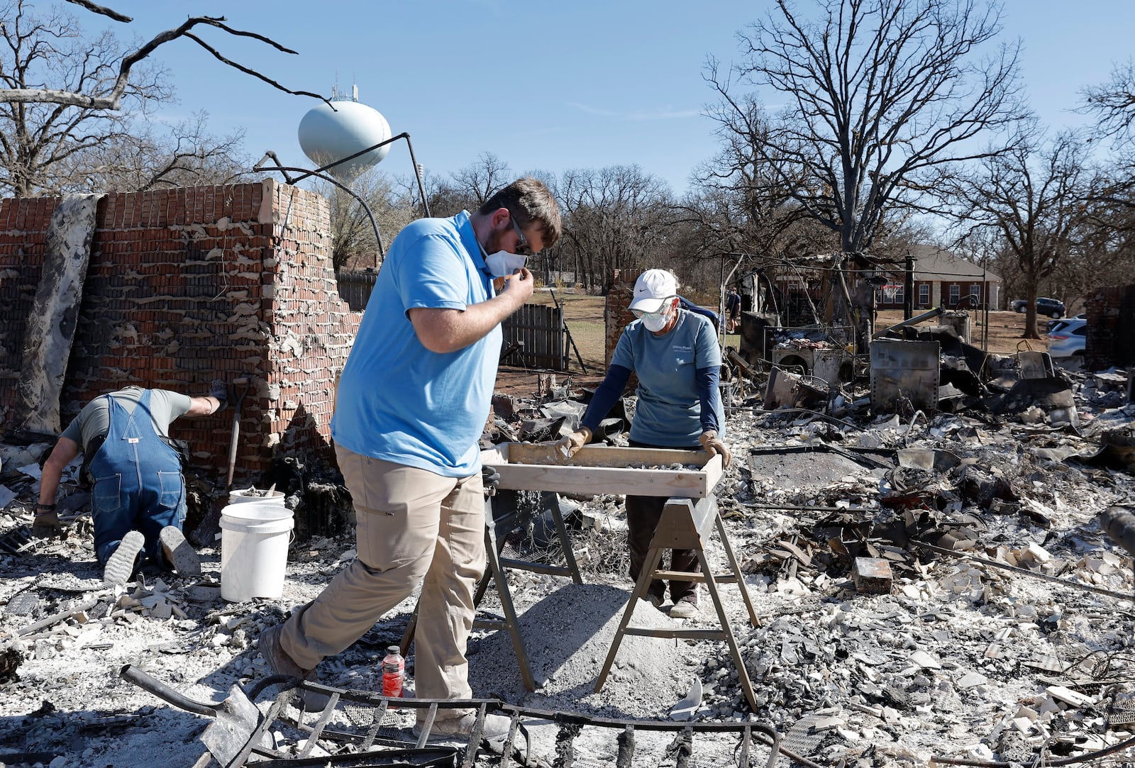 Cayton Jones, front, walks through the ashes that are left of his home in the Hidden Oaks neighborhood in Stillwater, Okla., on Monday, March 17, 2025, after wildfires burned through the area on Friday. (AP Photo/Alonzo Adams)