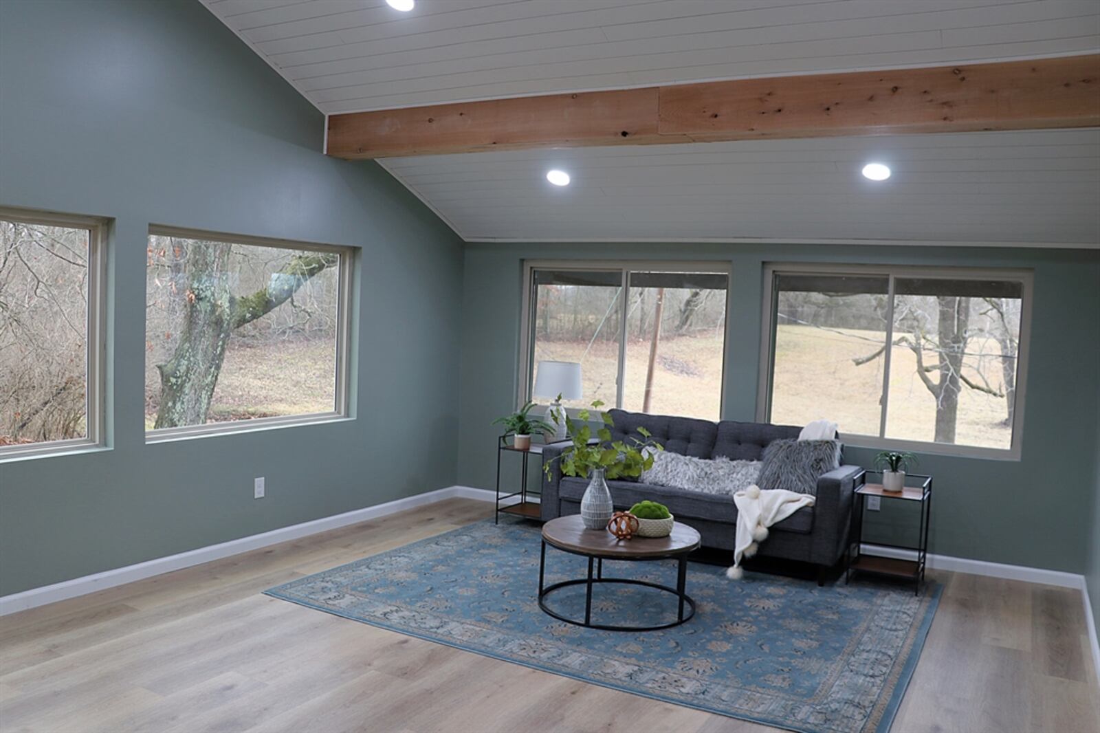 At the end of the hallway is a great room with a cathedral ceiling with bead-board and cedar beams. Seven picture windows give the room a sunroom effect, and oversized sliding patio doors open to the backyard.