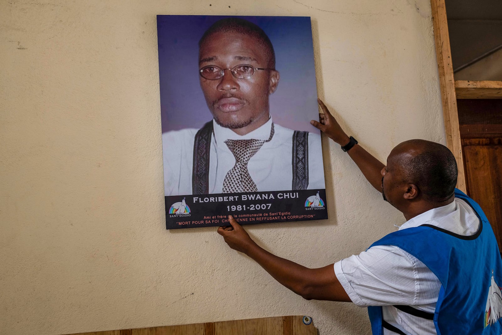 Jean Jacques Yack hangs a photo of Floribert Bwana Chui Bin Kositi, a Congolese man killed for fighting corruption in 2007, and whose beatification was approved by Pope Francis, in Goma, Democratic Republic of Congo, Sunday, Dec. 29, 2024. (AP Photo/Moses Sawasawa)