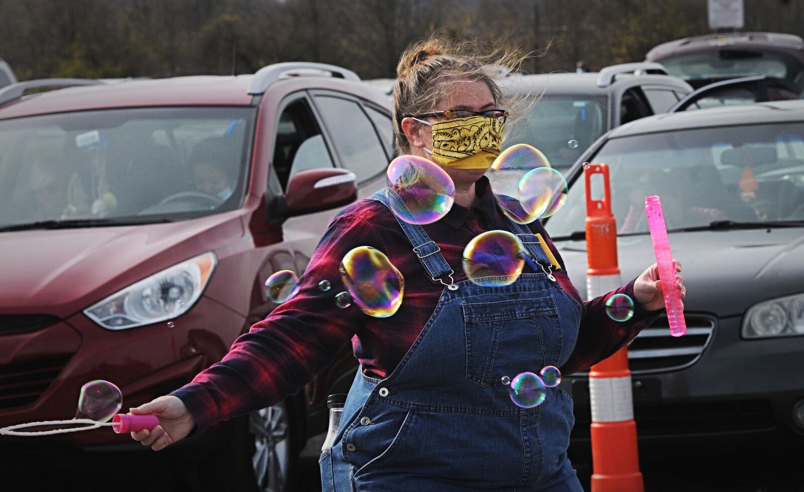 Jennifer White plays with bubbles while waiting for her free turkey at the former Kroger lot on Needmore Road Nov. 19, 2020. With God’s Grace Food Pantry is giving away 1,000 turkeys. MARSHALL GORBY\STAFF