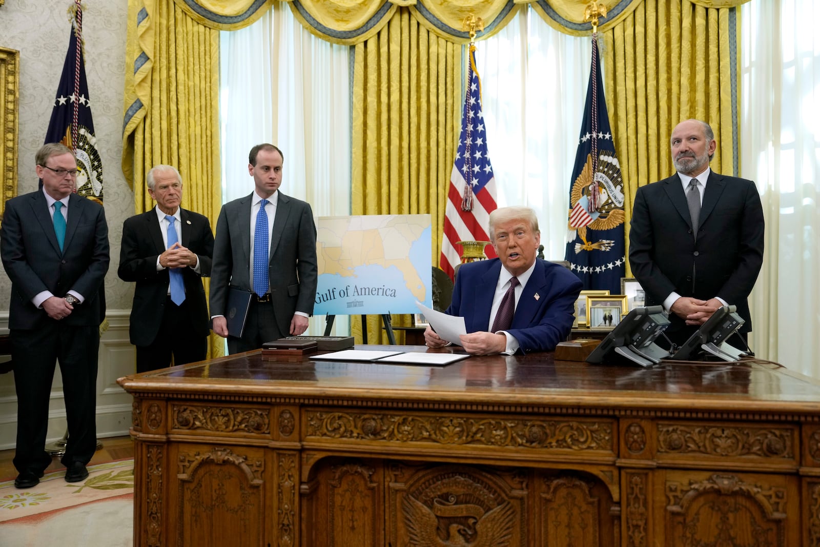 President Donald Trump speaks to reporters before signing an executive order as White House national economic council director Kevin Hassett, from left, White House senior counselor for trade and manufacturing Peter Navarro, White House staff secretary Will Scharf and Commerce Secretary nominee Howard Lutnick watch, in the Oval Office of the White House, Thursday, Feb. 13, 2025, in Washington. (AP Photo/Ben Curtis)