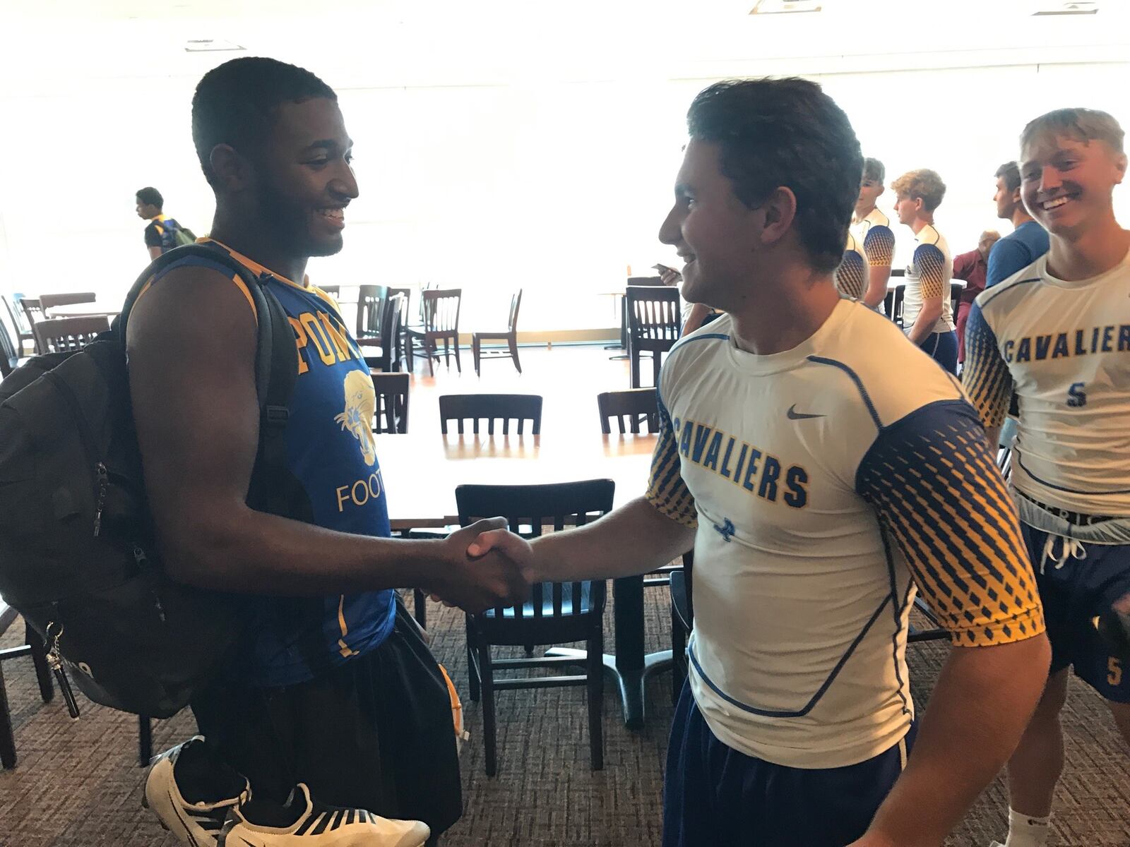 Cheyne Benson, a middle linebacker and running back at Ponitz High and Nathan Sollmann, a running back and strong safety at Sidney Lehman shake hands before parting ways after taking part in a lively social justice round table discussion in the Bosch Lounge at UD Arena Tuesday. It was part of the unique 7-on-7 Social Justice Football jamboree that was sponsored by the Miami Valley Football Coaches Association. (Photo by Tom Archdeacon)