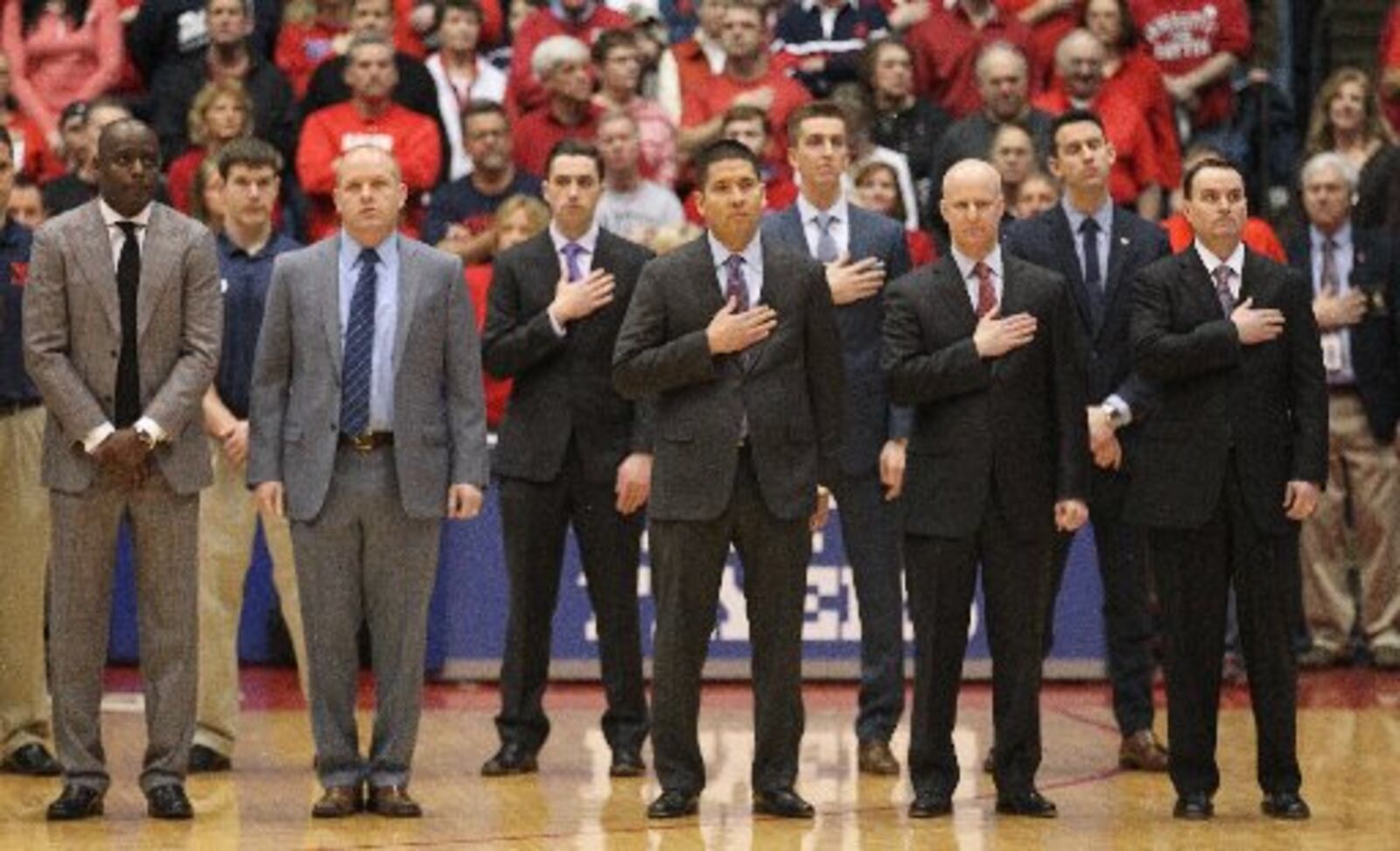 Dayton coaches stand for the national anthem before a game against La Salle on Saturday, Jan. 30, 2016, at UD Arena in Dayton. From left to right: Allen Griffin, Kevin Kuwik, Tom Ostrom, Bill Comar and Archie Miller. In the second row are coaches Ben Sander, Brian Walsh and Brian Frank. David Jablonski/Staff