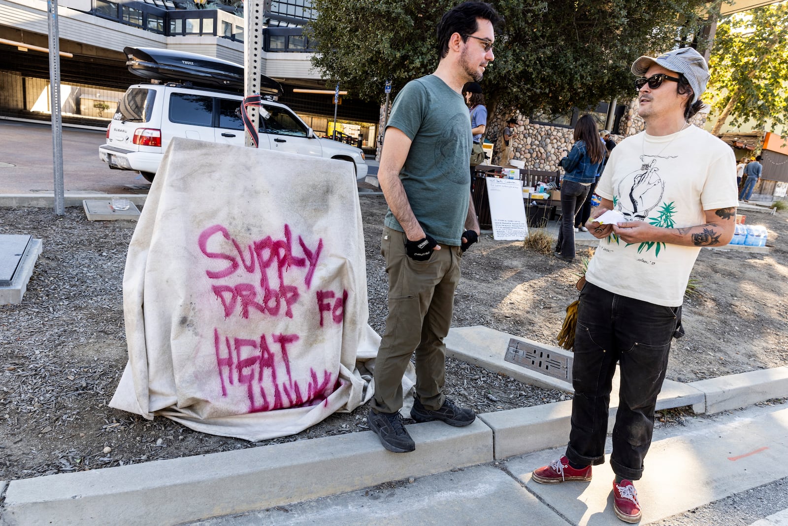 Bobby Ognyanov, left, chats with Cody "Toad" Webb outside Topanga Library as a volunteer group known as the Heat Hawks organizes mutual aid to the community during the Palisades Fire in Topanga, Calif., Thursday, Jan. 9, 2025. (Stephen Lam/San Francisco Chronicle via AP)