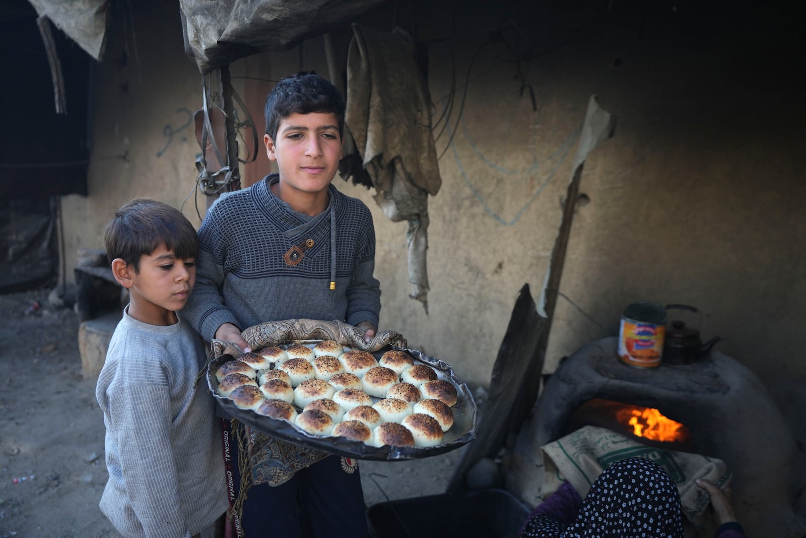 A Palestinian boy carries a tray of baked goods from a clay oven amid dire food shortages in Deir al-Balah, Gaza Strip, Monday, Dec. 2, 2024. (AP Photo/Abdel Kareem Hana)