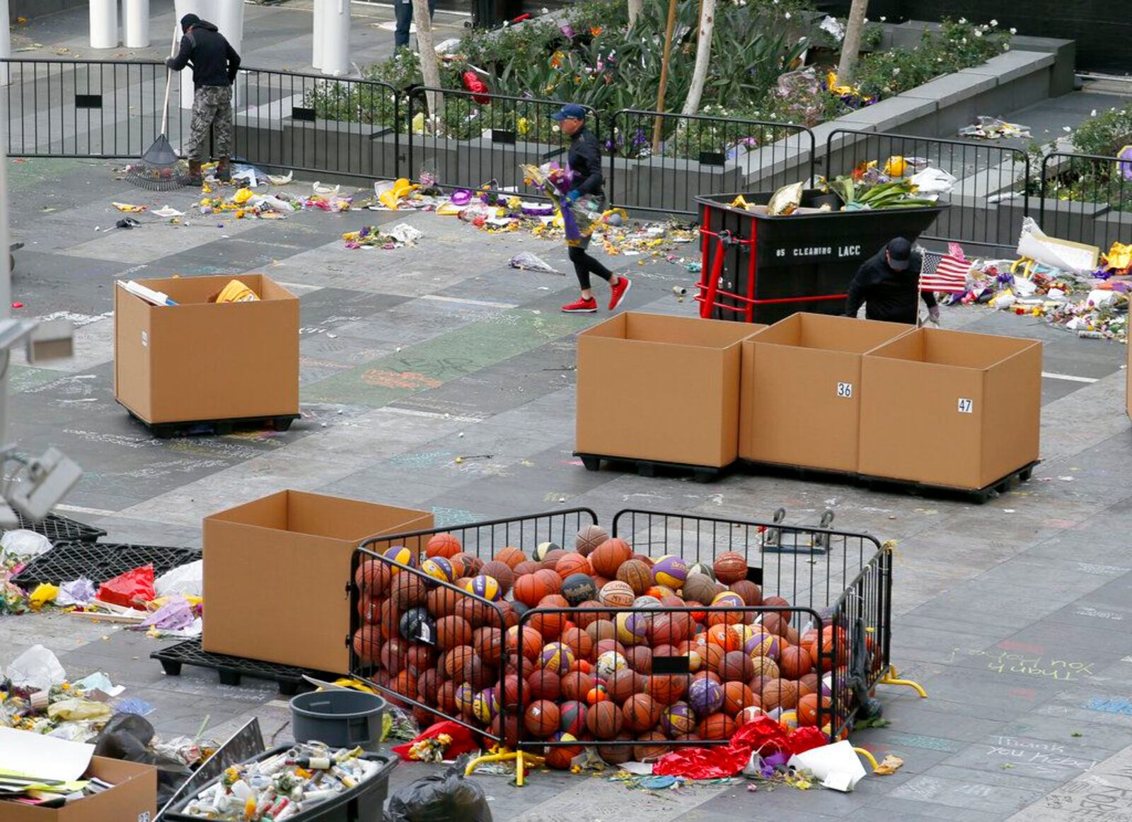 Workers remove thousands of items left in honor of Kobe Bryant, including hundreds of basketballs, from X-Box Plaza across Chick Hearn Court from Staples Center, home of the Los Angeles Lakers, early Monday, Feb. 3, 2020, in Los Angeles. Mourners left the items after the death of the former Lakers legend, his daughter and seven others, in a helicopter crash one week ago.