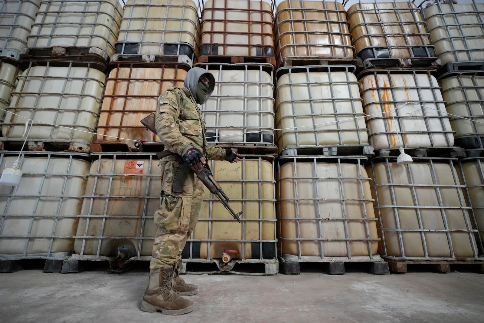 A Syrian member of the rebel group shows liquid material for manufacturing amphetamine pills known as Captagon hidden, at the warehouse where the drug was manufactured before the fall of Bashar Assad government at a facility in Douma city, outskirts of Damascus, Syria, Friday, Dec. 13, 2024. (AP Photo/Hussein Malla)