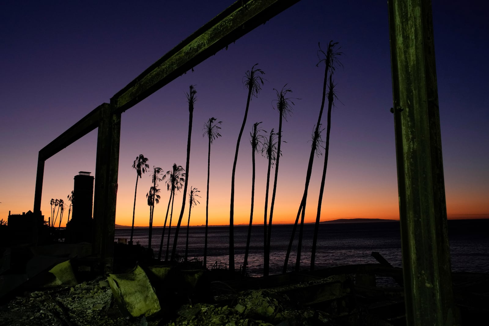 The sun rises behind a fire-ravaged beachfront property in the aftermath of the Palisades Fire Monday, Jan. 13, 2025 in Malibu, Calif. (AP Photo/John Locher)