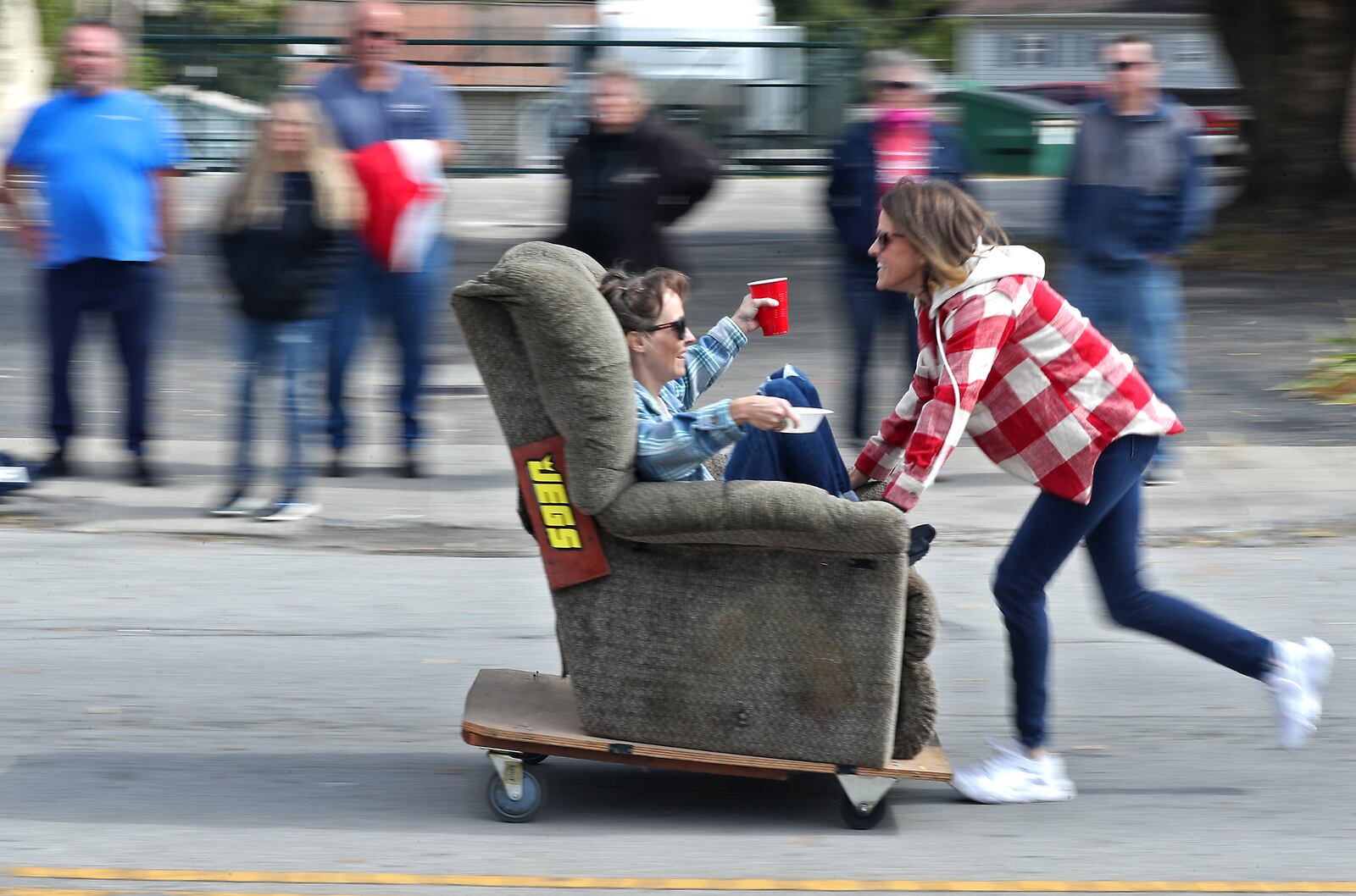 Charity Notestine pushes Brook Eggleston backward in a recliner on wheels down Main Street in New Carlisle Sunday, Oct. 2, 2022. One of the highlights of the New Carlisle Heritage of Flight Festival every year is the Jim Slanker Memorial Chair Races. BILL LACKEY/STAFF