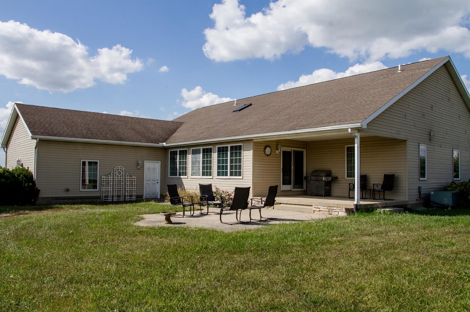 The rear of the home has a covered concrete patio and a concrete extension and overlooks farm fields and more than six acres of property. The home includes a wooden child's playset and a trampoline. CONTRIBUTED