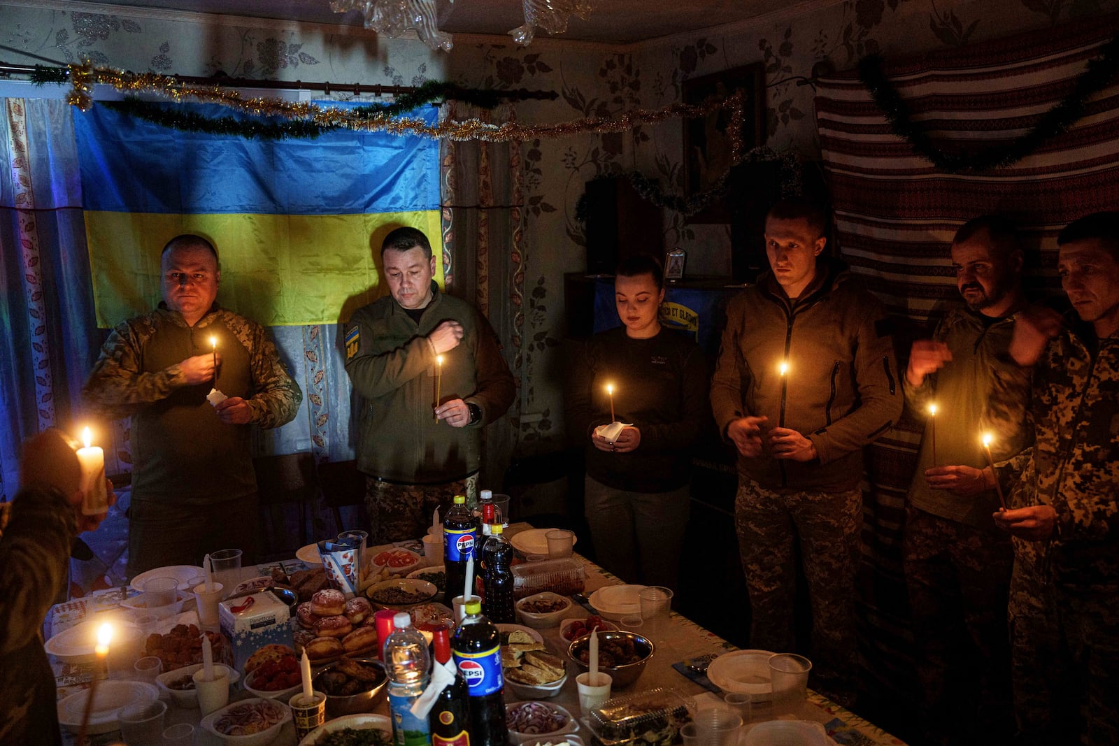 Ukrainian servicemen of 117th Separate Heavy Mechanized Brigade pray before a Christmas dinner on Pokrovsk direction, Donetsk region, Ukraine, Tuesday, Dec. 24, 2024. (AP Photo/Evgeniy Maloletka)