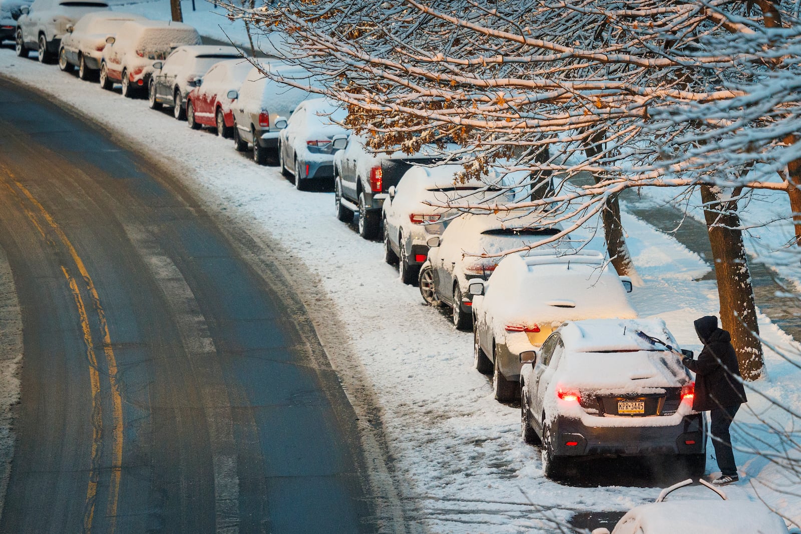 A driver removes snow from a car before pulling away from parking spot after overnight snow fall covered street and vehicles in Philadelphia, Wednesday, Feb. 12, 2025. (Alejandro A. Alvarez/The Philadelphia Inquirer via AP)