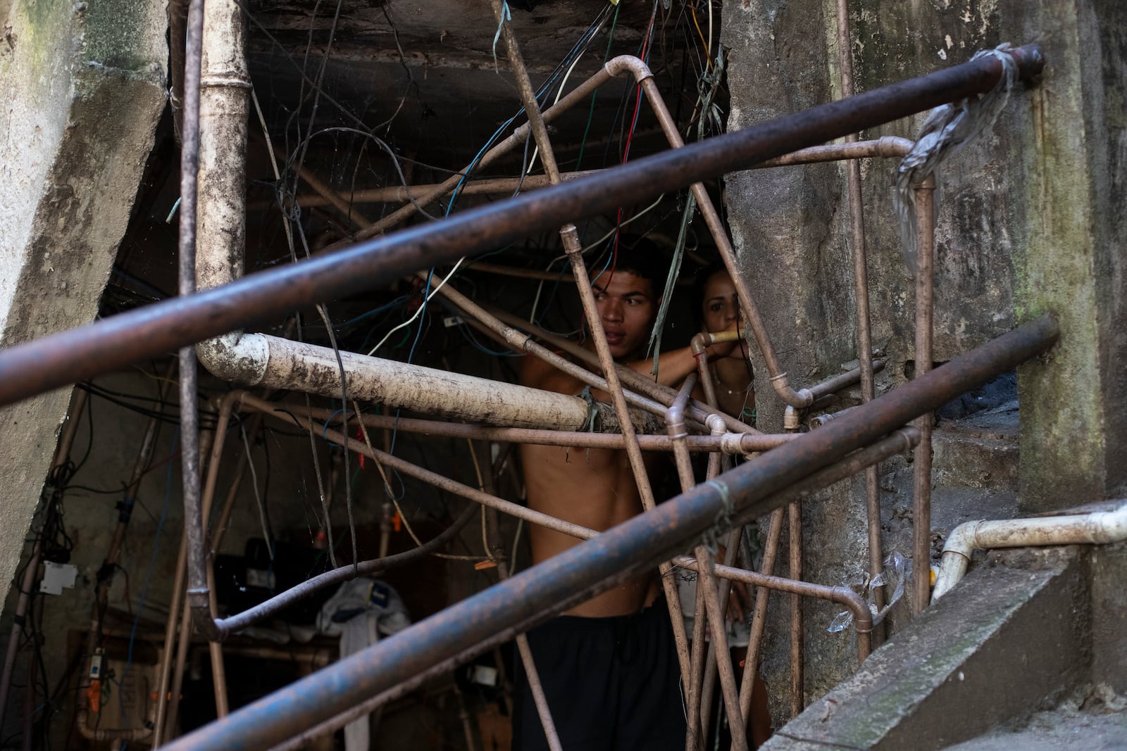 Residents repair a water line to their home amid a labyrinth of pipes in the Rocinha favela of Rio de Janeiro, Wednesday, Nov. 6, 2024. (AP Photo/Bruna Prado)