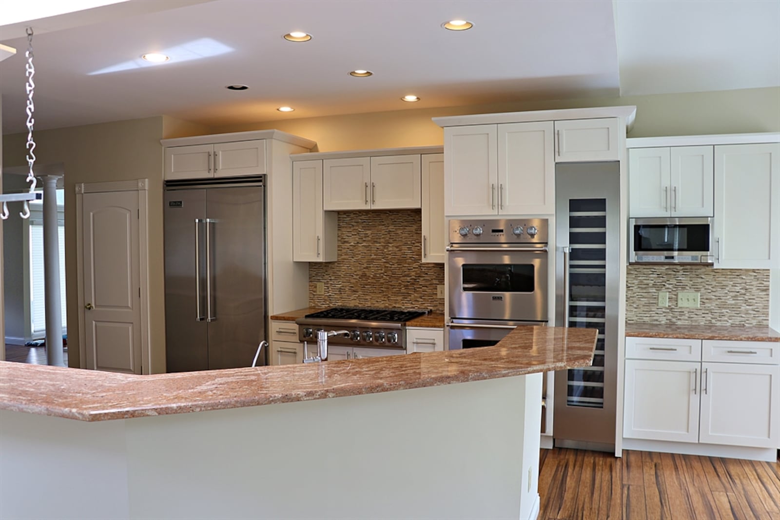 In the kitchen, a double sink is below a two-level peninsula counter, which offers breakfast bar seating and divides the kitchen from the bay-like breakfast room and the great room. 