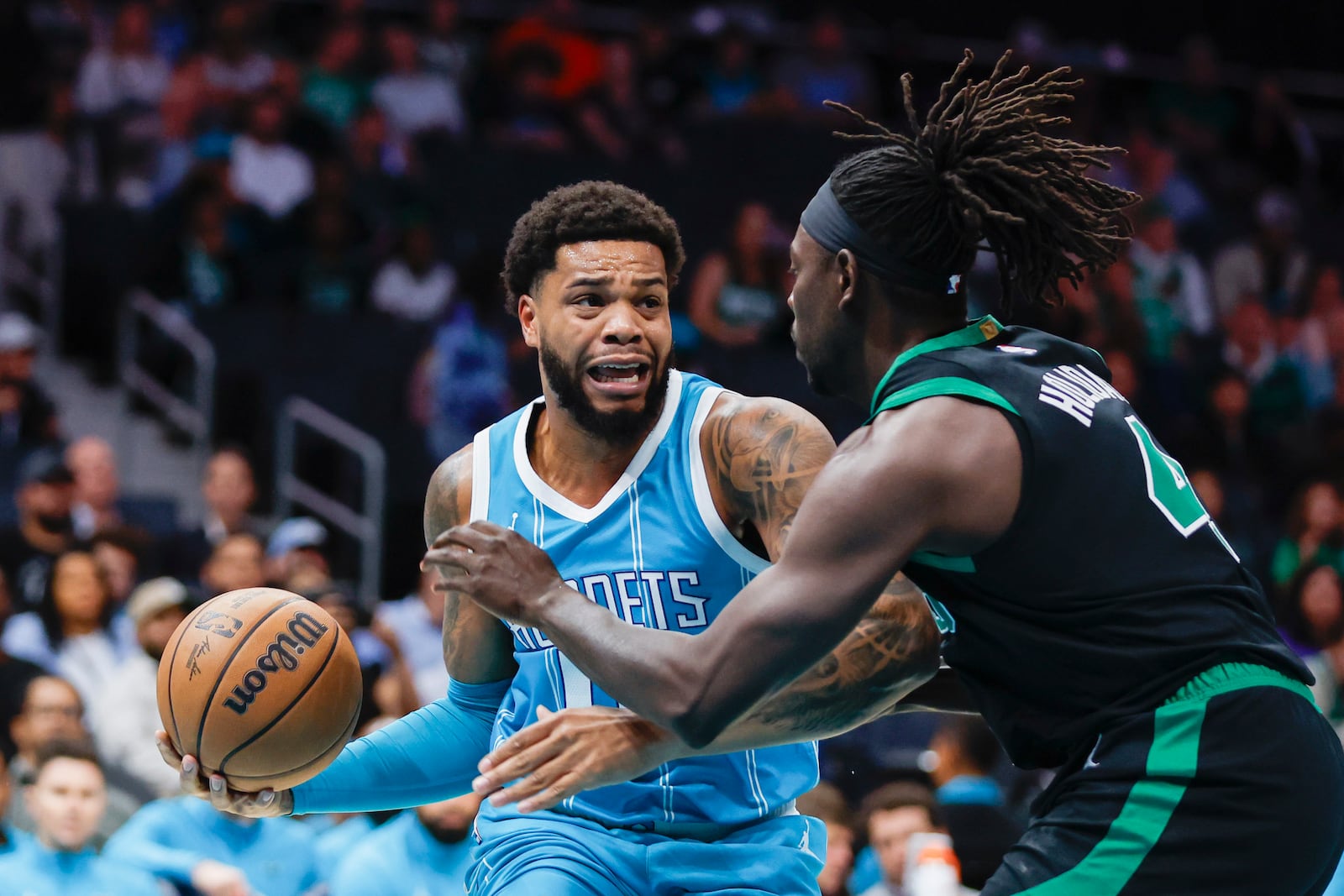 Charlotte Hornets forward Miles Bridges, left, drives against Boston Celtics guard Jrue Holiday during the first quarter of an NBA basketball game in Charlotte, N.C., Friday, Nov. 1, 2024. (AP Photo/Nell Redmond)