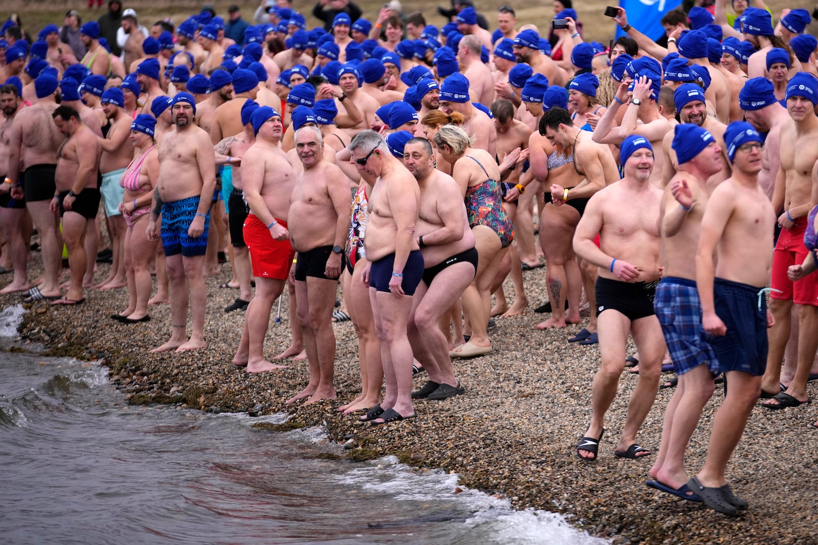 Some of 2461 polar swimmers get in the water to set a world record for the largest polar bear dip at a lake in Most, Czech Republic, Saturday, March 1, 2025. (AP Photo/Petr David Josek)