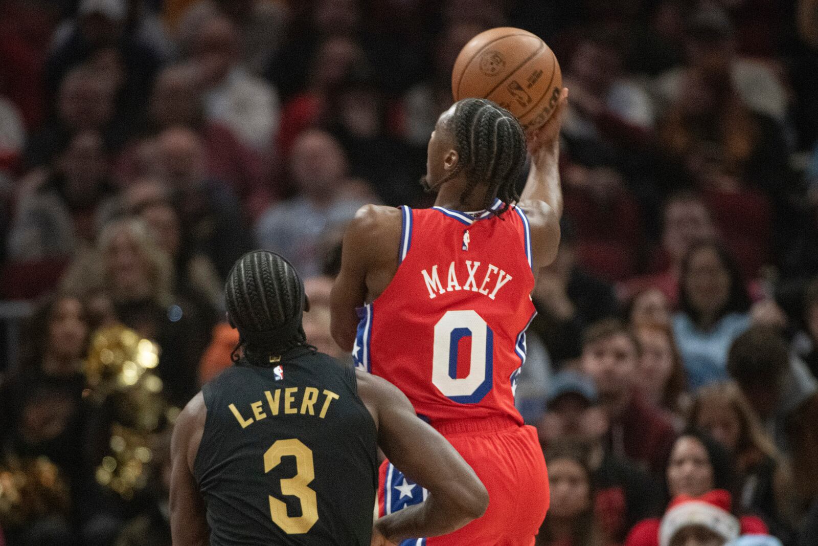 Philadelphia 76ers' Tyrese Maxey (0) shoots as Cleveland Cavaliers' Caris LeVert (3) looks on during the first half of an NBA basketball game in Cleveland, Saturday Dec. 21, 2024. (AP Photo/Phil Long)