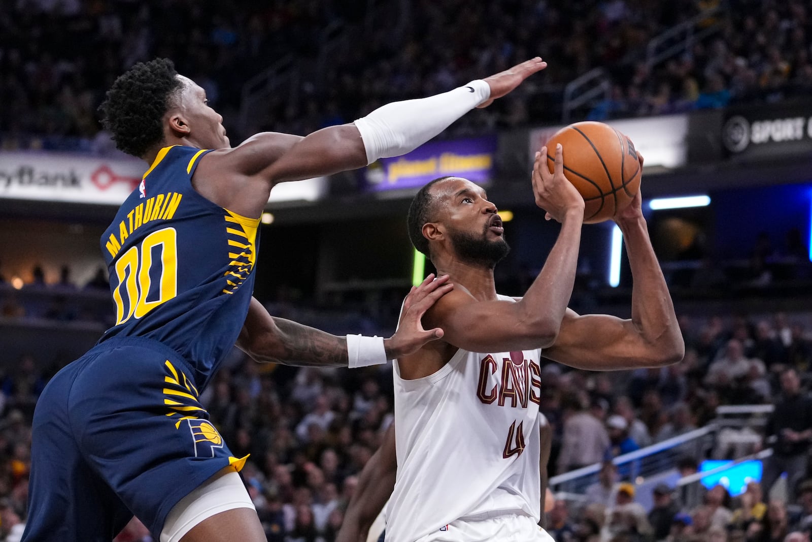 Indiana Pacers guard Bennedict Mathurin (00) tries to stop the shot of Cleveland Cavaliers forward Evan Mobley (4) during the second half of an NBA basketball game in Indianapolis, Tuesday, Jan. 14, 2025. (AP Photo/Michael Conroy)