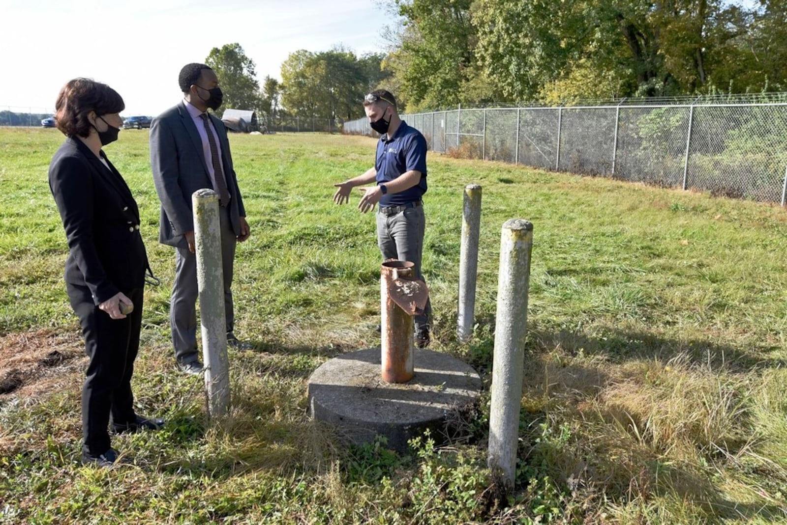 In this 2020 photo, Treva Bashore, restoration program manager, 88th Air Base Wing Civil Engineer Center (left), Amir Mott, deputy director, 88th Civil Engineer Group (center), and Dan Casey, lead field operations engineer, discuss a monitoring well at the fire training area of Wright-Patterson Air Force Base. (U.S. Air Force photo by Ty Greenlees)