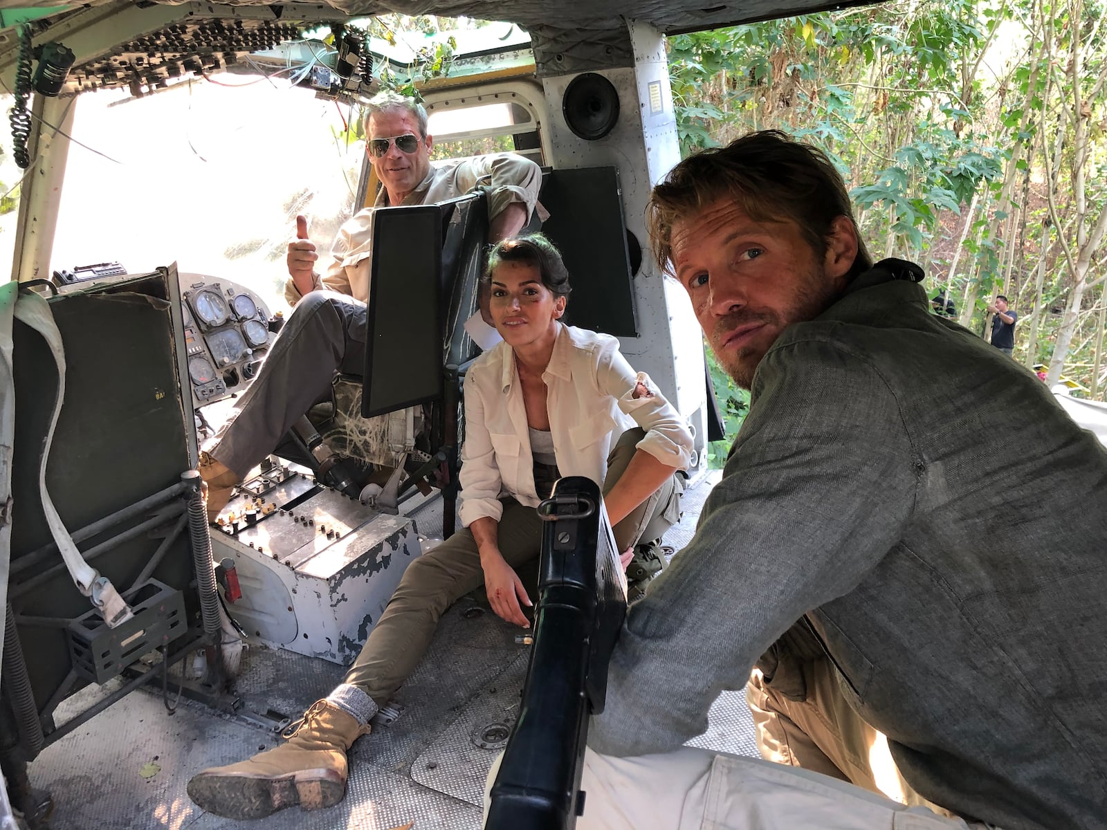 The cast of “Blood & Treasure,” (left to right) Mark Valley, Sofia Pernas and Matt Barr, inside a  Huey on a set outside of Kanchanburi, Thailand.