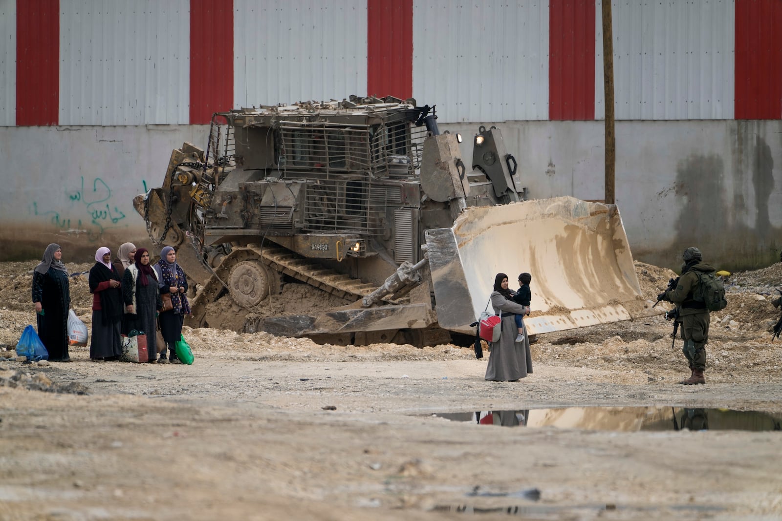 Israeli soldiers check the ID of Palestinians in the West Bank refugee camp of Nur Shams, Tulkarem, as the Israeli military continues its operation in the area on Tuesday, Feb. 11, 2025. (AP Photo/Majdi Mohammed)