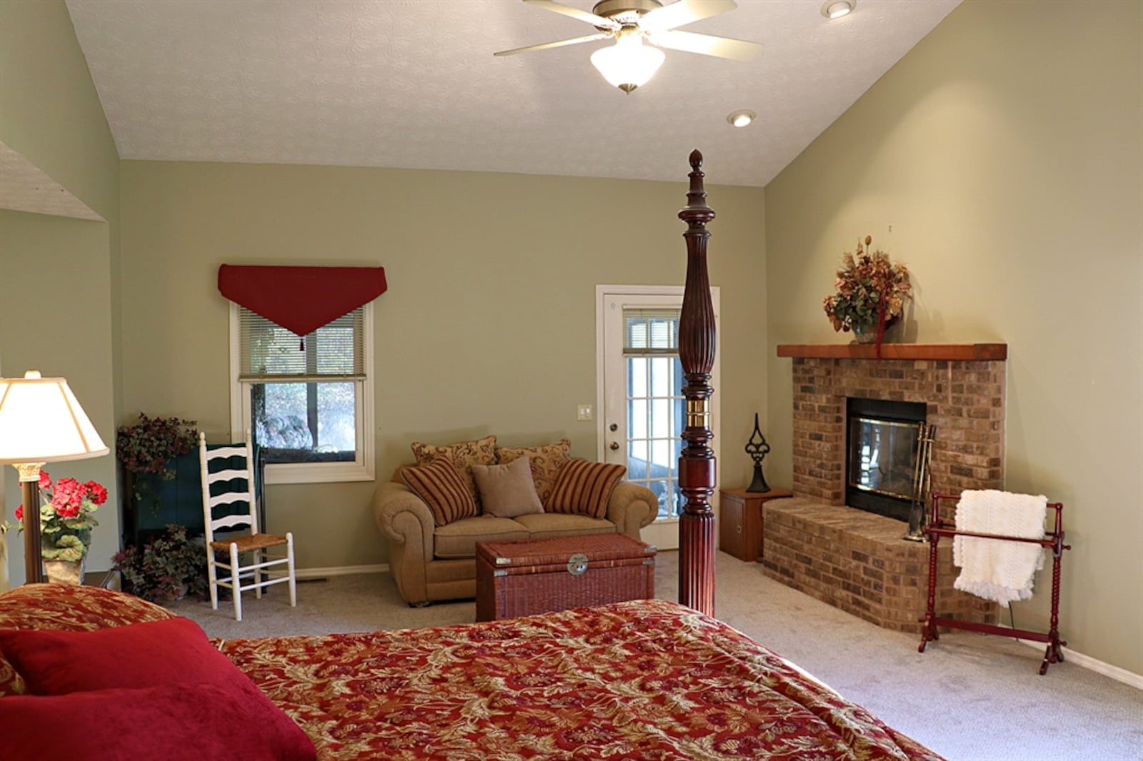 The main bedroom has a cathedral ceiling and a brick wood-burning fireplace with raised hearth and wood-beam mantel. 