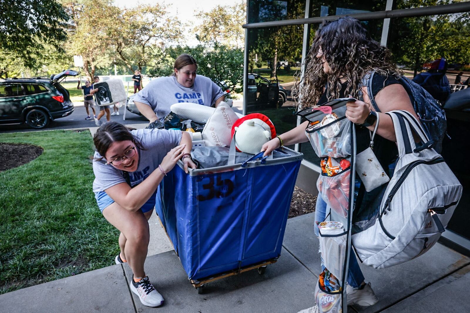 From left, Sophie Morgan, Lily Kuebler and Mackenzie Rogers, all freshman at the University of Dayton lift a heavy tote to Stuart Hall on freshman move in day Friday August 18, 2023. JIM NOELKER/STAFF