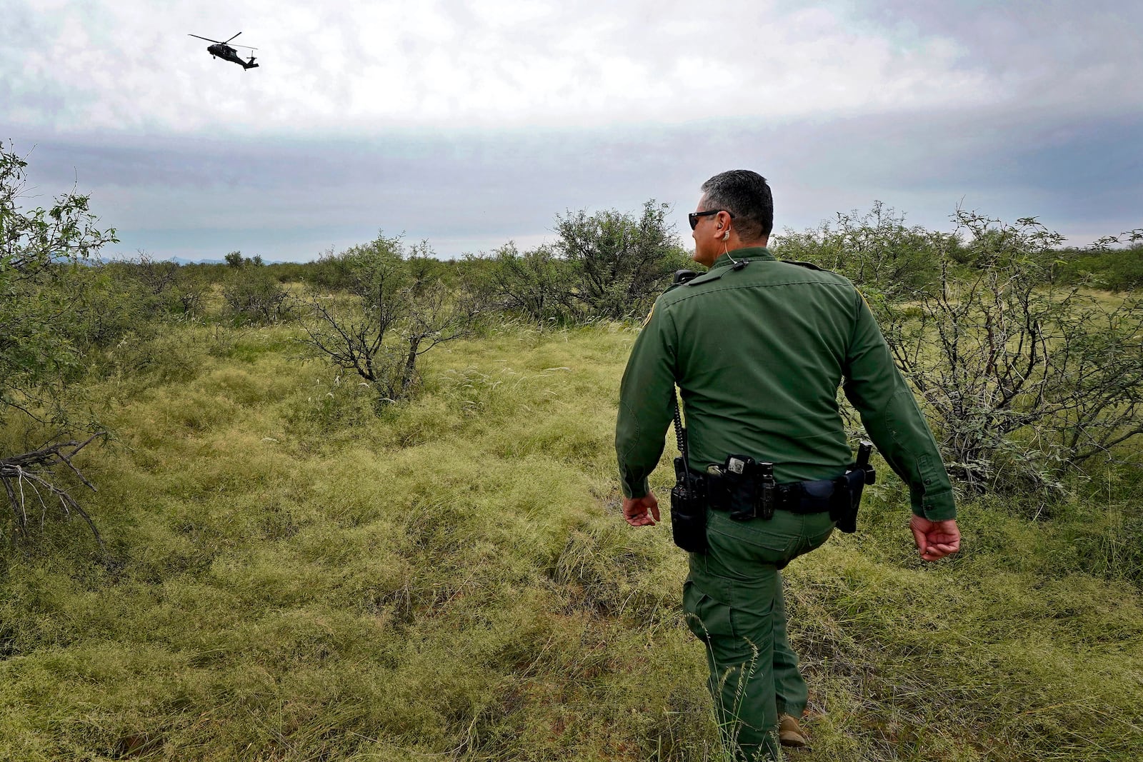 U.S. Border Patrol agent Jesus Vasavilbaso, aided by a Black Hawk helicopter, searches for a group of migrants evading capture in the desert brush at the base of the Baboquivari Mountains, Thursday, Sept. 8, 2022, near Sasabe, Ariz. (AP Photo/Matt York, File)