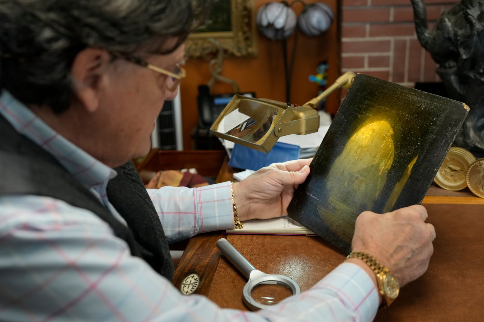 A small oil painting is examined by appraiser Kaja Veilleux for a client at Thomaston Place Auction Galleries, Tuesday, Nov. 19, 2024, in Thomaston, Maine. (AP Photo/Robert F. Bukaty)