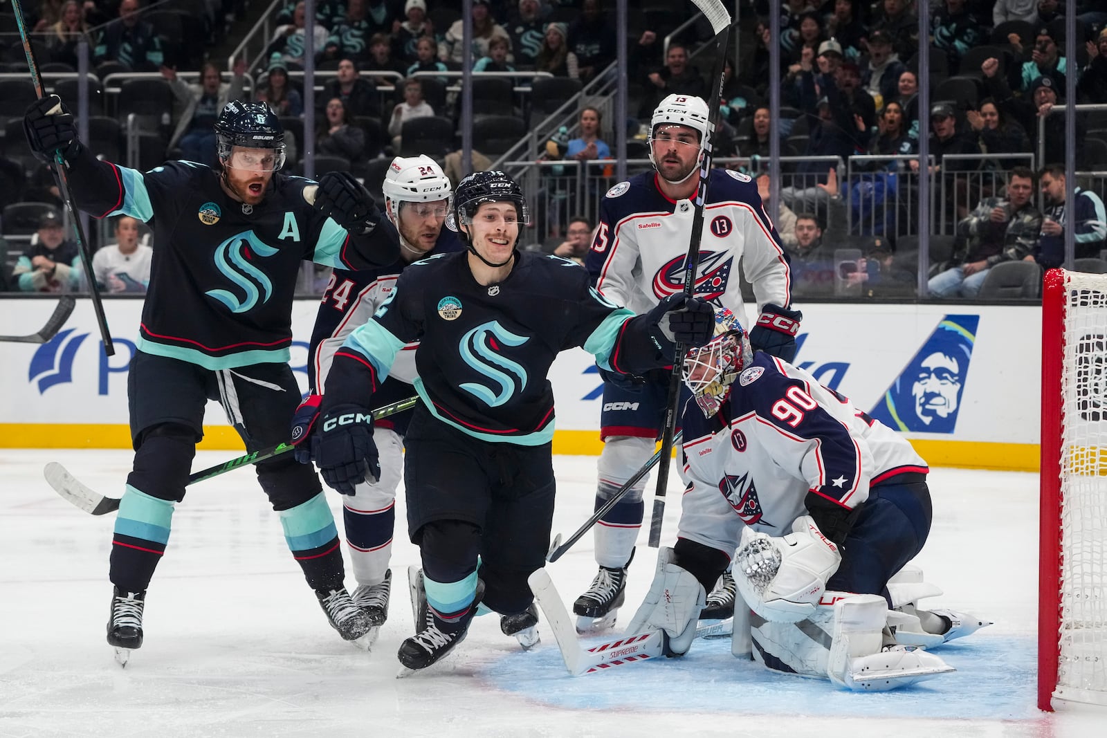 Seattle Kraken left wing Tye Kartye, third from left, celebrates his goal with defenseman Adam Larsson, left, as Columbus Blue Jackets right wing Mathieu Olivier (24), defenseman Dante Fabbro (15) and goaltender Elvis Merzlikins (90) look on during the second period of an NHL hockey game Tuesday, Nov. 12, 2024, in Seattle. (AP Photo/Lindsey Wasson)